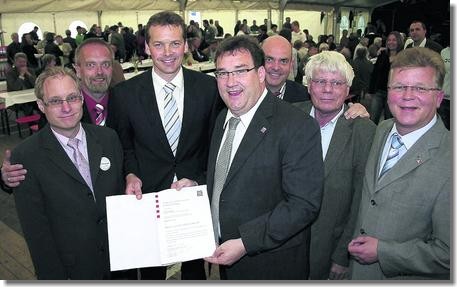 Gruppenfoto mit Personen, die die Urkunde in die Kamera halten